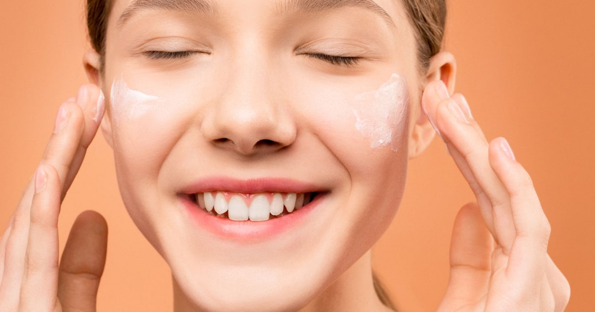 A woman gently applying face cream during her skincare routine.